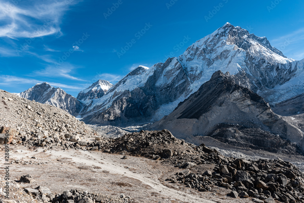 Hiking trail through a valley in the Himalayan mountains of Nepal surrounded by rocky terrain and glaciers