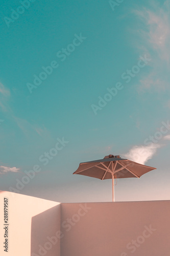 Sun parasol on a white washed balcony against blue sky. Minimal Architecture of Mykonos  Santorini and the Cyclades. 