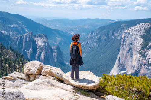 A young woman in pink and black at Sentinel Dome looking at El Capitan, Yosemite National Park. United States