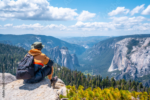A young man sitting at the Sentinel Dome viewpoint in Yosemite National Park. United States