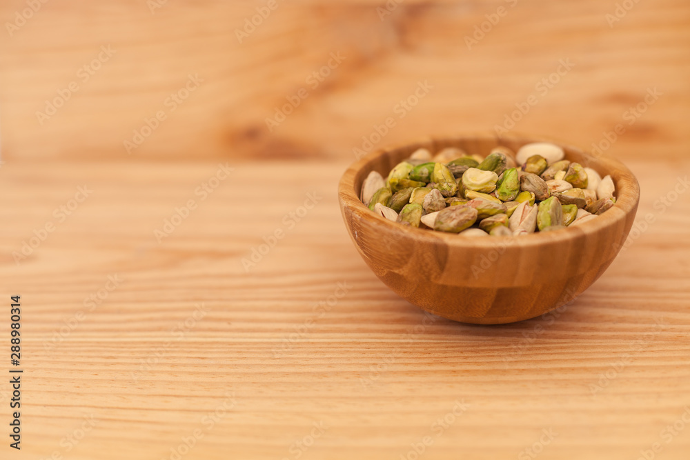 Shell and peeled pistachios in wooden bowl Shell and peeled pistachios in wooden bowl