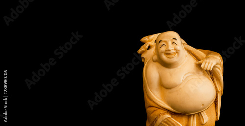 Budai, the "Laughing Buddha" figurine on black background with copy space