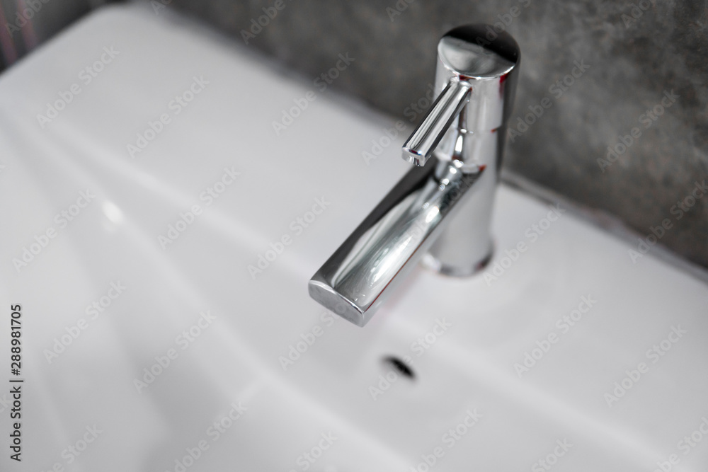 Modern stainless steel faucet with wash basin sink. Counter bathroom interior contemporary. Luxury and stylish design bathroom with a concrete style walls. Modern stainless steel faucet with wash basin sink. Counter bathroom interior contemporary. Luxury and stylish design bathroom with a concrete style walls.