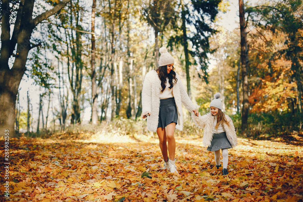 Fototapeta premium Beautiful mother with daughter. Family in a autumn park. Golden autumn
