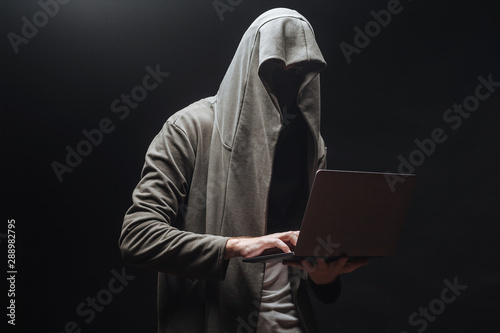 Criminal with laptop in hood at night