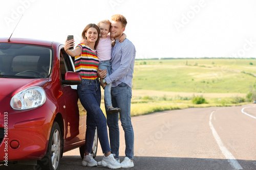 Happy young family taking selfie near car on road trip © New Africa