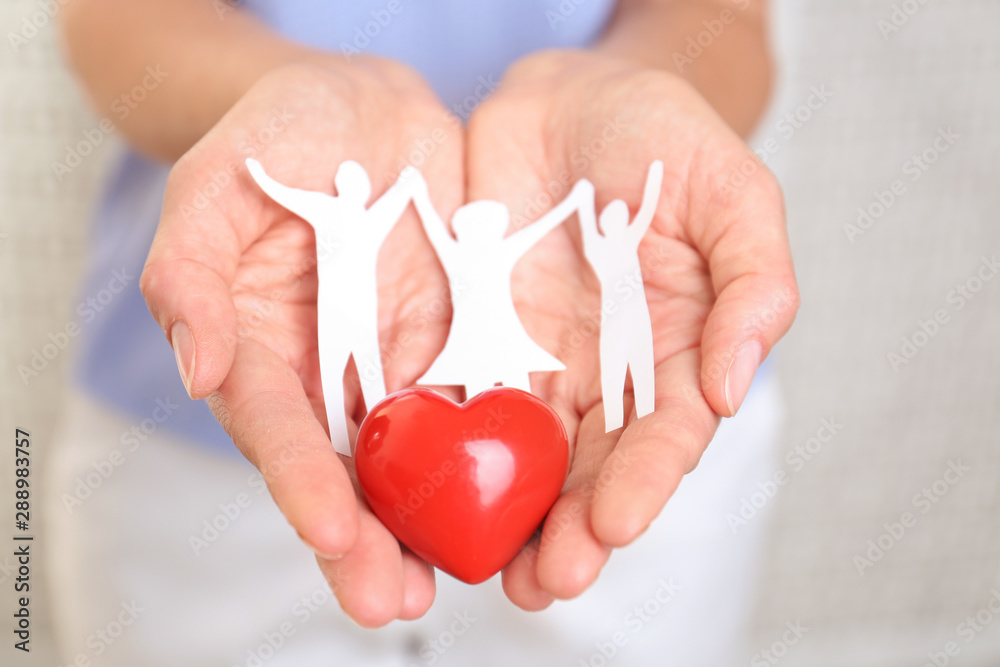 Young woman holding paper family figure and red heart, closeup of hands Young woman holding paper family figure and red heart, closeup of hands