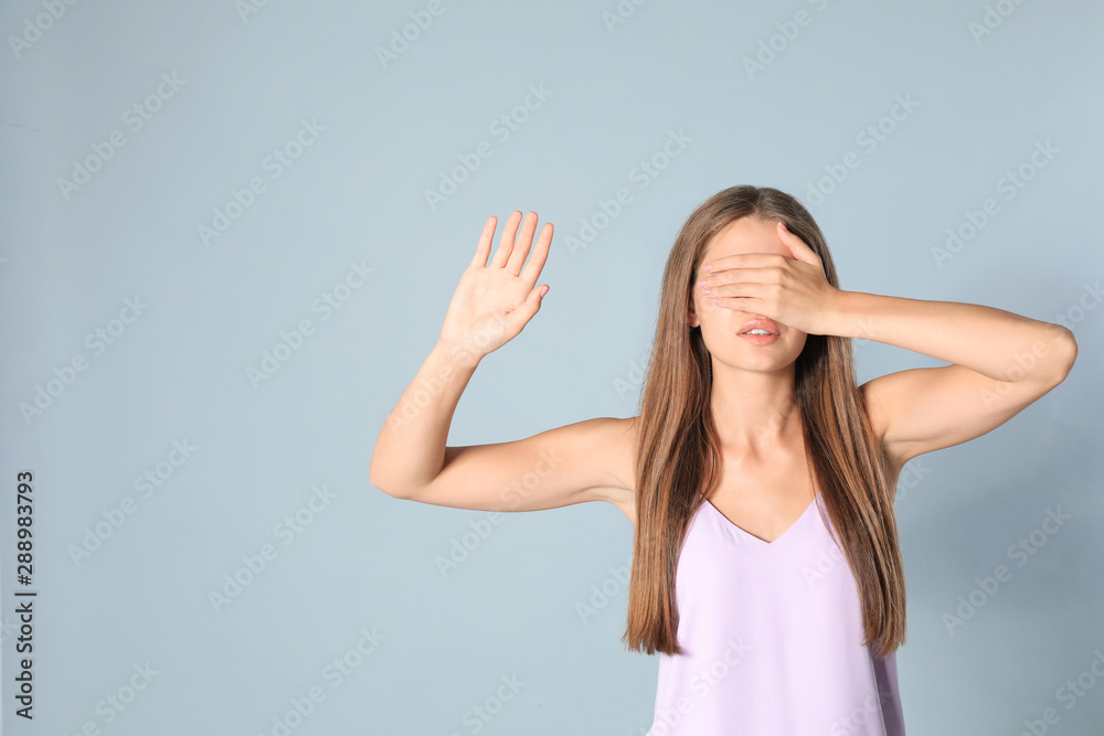 Young woman being blinded on grey background, space for text Young woman being blinded on grey background, space for text