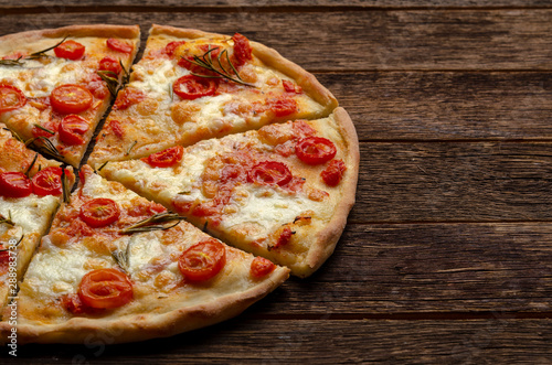 cutting Italian pizza on wooden background. Cherry tomatoes, parmesan cheese