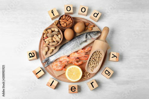 Flat lay composition of different products and wooden cubes with words FOOD ALLERGY on white table photo