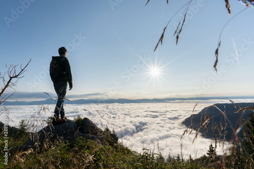 hiker standing on the top of a mountain and enjoying an amazing view over a cloud covered valley. Luck happiness and freedom concept in South Tyrol Italy