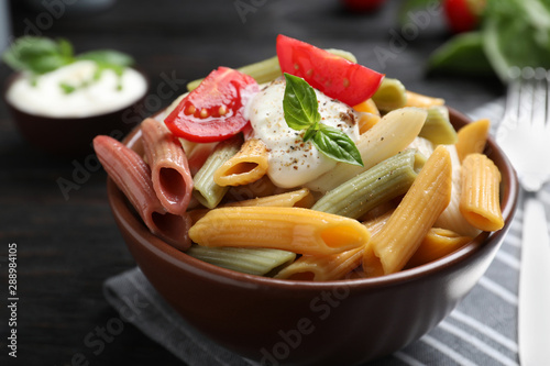 Delicious vegetable pasta with sour cream dressing on black wooden table, closeup