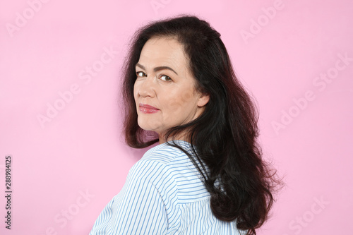 Portrait of mature woman with beautiful face on pink background