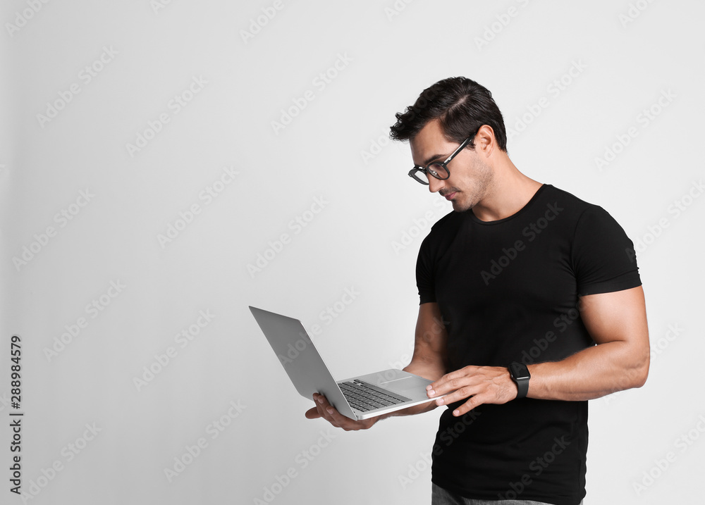 Handsome young man with laptop on grey background. Space for text Handsome young man with laptop on grey background. Space for text