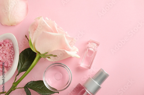 Flat lay composition with rose essential oil on pink background, space for text