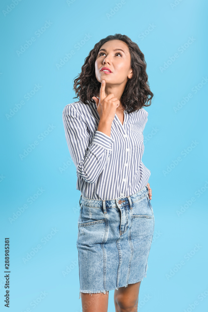 Thoughtful young woman in casual outfit on blue background Thoughtful young woman in casual outfit on blue background