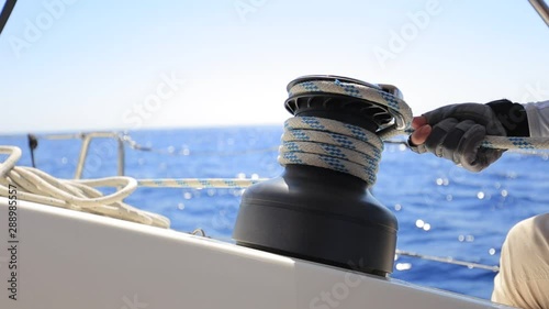 Yachtsman hands dealing with yacht ropes on halyard winch