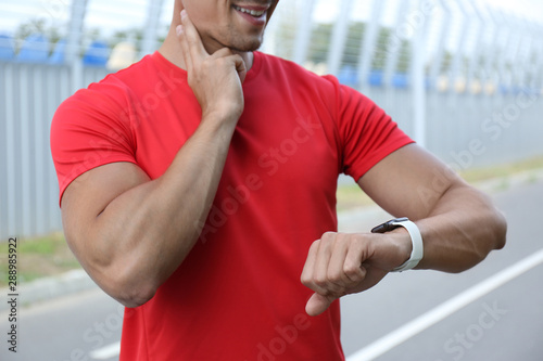 Young man checking pulse after training outdoors, closeup © New Africa