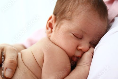 Young mother with her little baby on light background, closeup