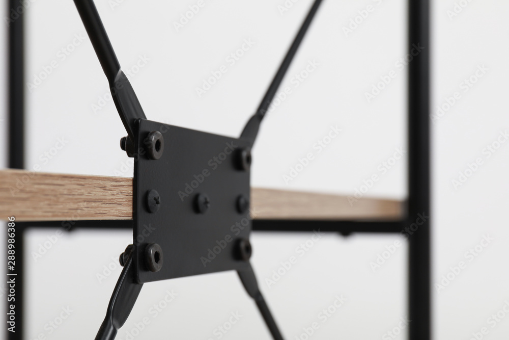 Rack with black metal connecting detail on light background, closeup