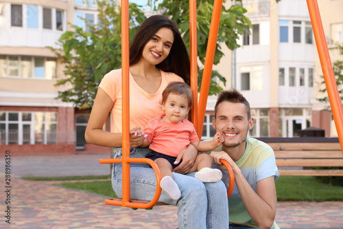 Happy family with adorable little baby at playground