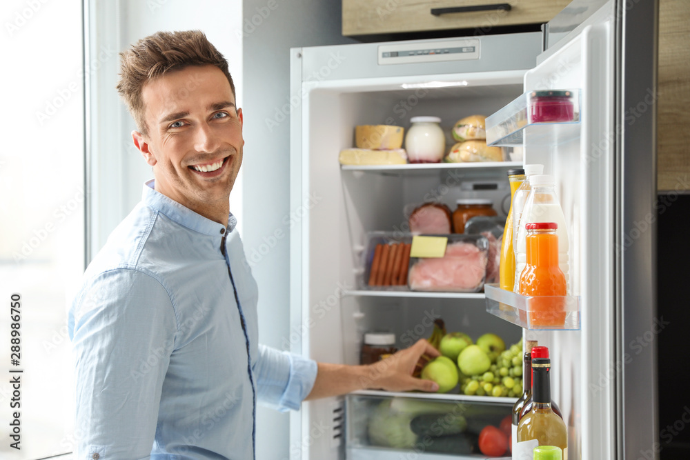 Man taking apple out of refrigerator in kitchen