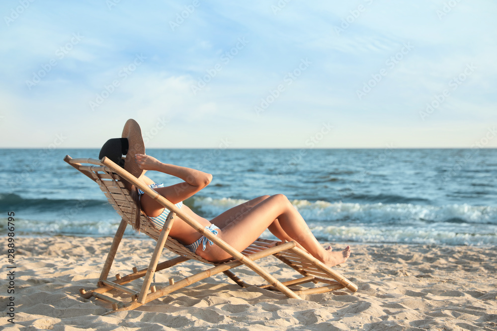Young woman relaxing in deck chair on beach