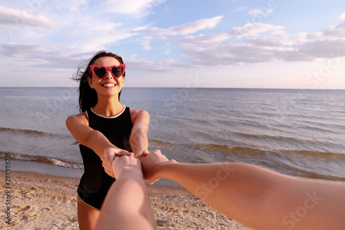 Young woman holding hands with girlfriend on beach