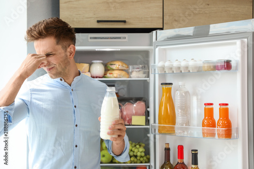 Bild auf Leinwand Man taking bottle with old milk out of refrigerator in kitchen