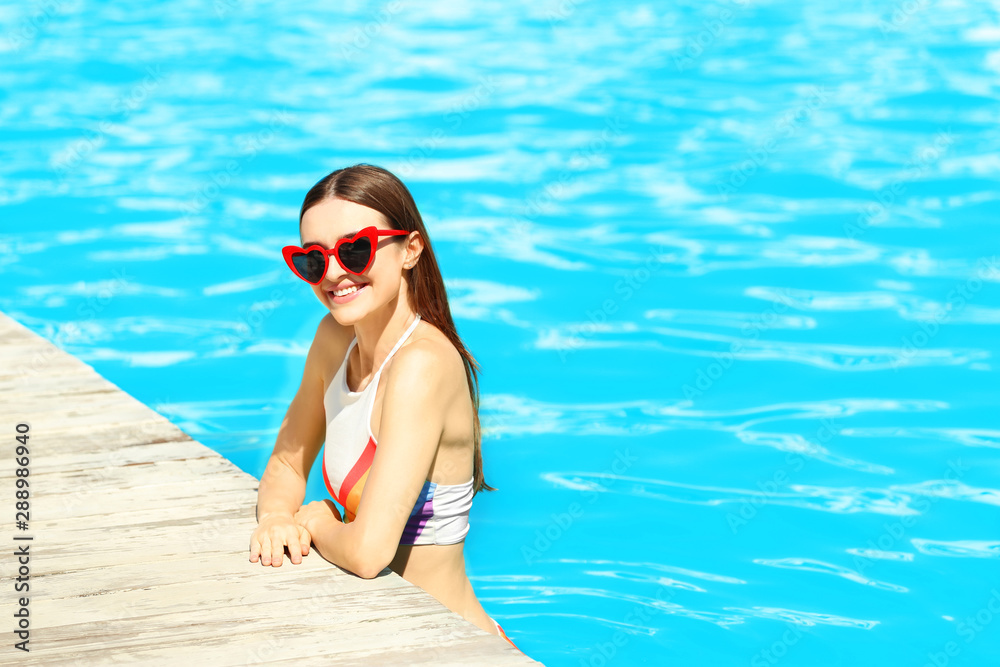 Beautiful young woman in swimming pool on sunny day