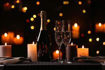 Romantic dinner table setting with burning candles and festive lights
