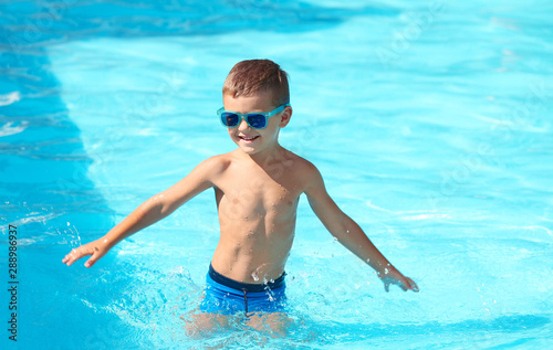 Happy little boy having fun in swimming pool