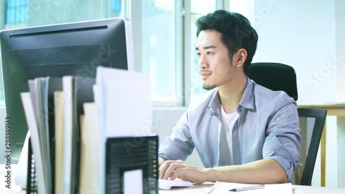 young asian business man working in office using desktop computer photo