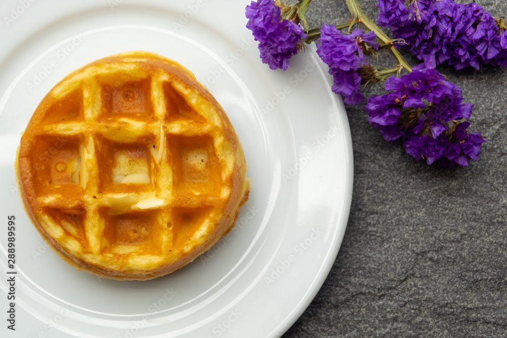 vanilla waffle on a white plate with purple flower, fresh baked for sweet meal, dessert concept. vanilla waffle on a white plate with purple flower, fresh baked for sweet meal, dessert concept.