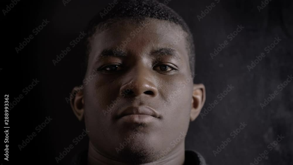 Defocued Confident angry african american man looking at camera in the dark Defocued Confident angry african american man looking at camera in the dark