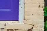 Purple door with aged white brick wall