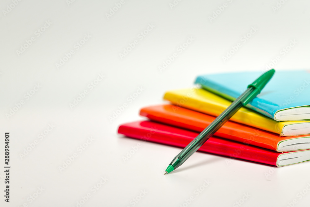 Pila de libretas de colores con pluma