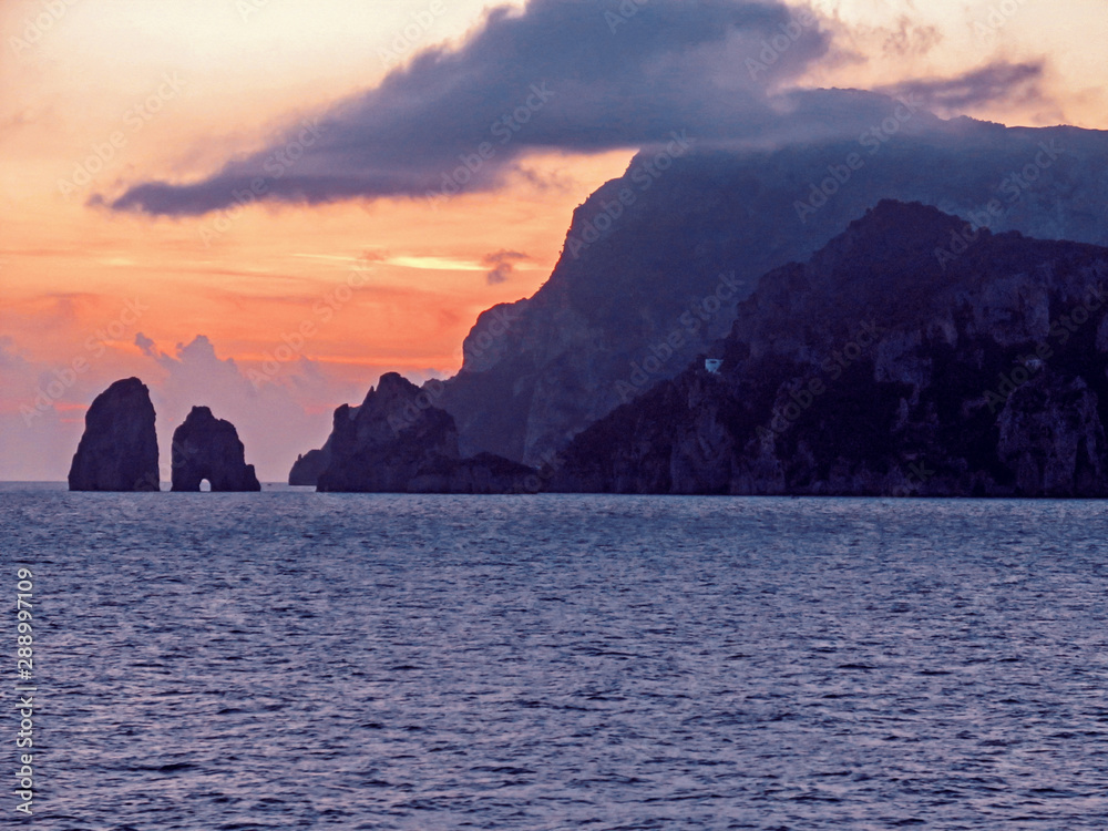 Capri Island near Naples, Italy. Beautiful sunset and landscape with sea, mountain and bright sky. Panoramic view from the water surface.