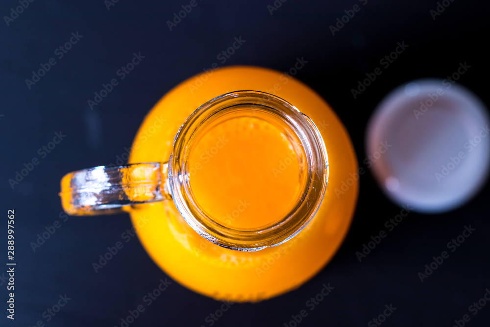 Suco Concentrado de tangerina na garrafa com as frutas sobre a mesa de madeira cor de carvão Suco Concentrado de tangerina na garrafa com as frutas sobre a mesa de madeira cor de carvão