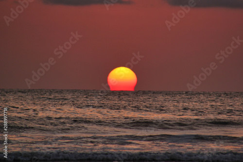 Fototapeta Naklejka Na Ścianę i Meble -  Sunset over the sea with the sun melting in the ocean