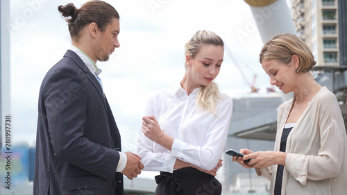 Group of Business people meeting and negotiate business in the CBD (Central Business District) with surrounded by tall buildings. Businessman and Businesswoman are standing and talking each happily.