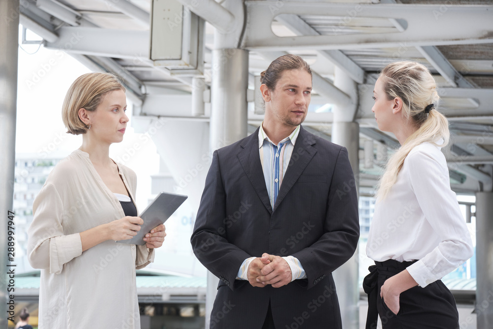 Group of Business people meeting and negotiate business in the CBD (Central Business District) while walking at the skywalk. Businessmen and Businesswomen are standing and talking each happily.