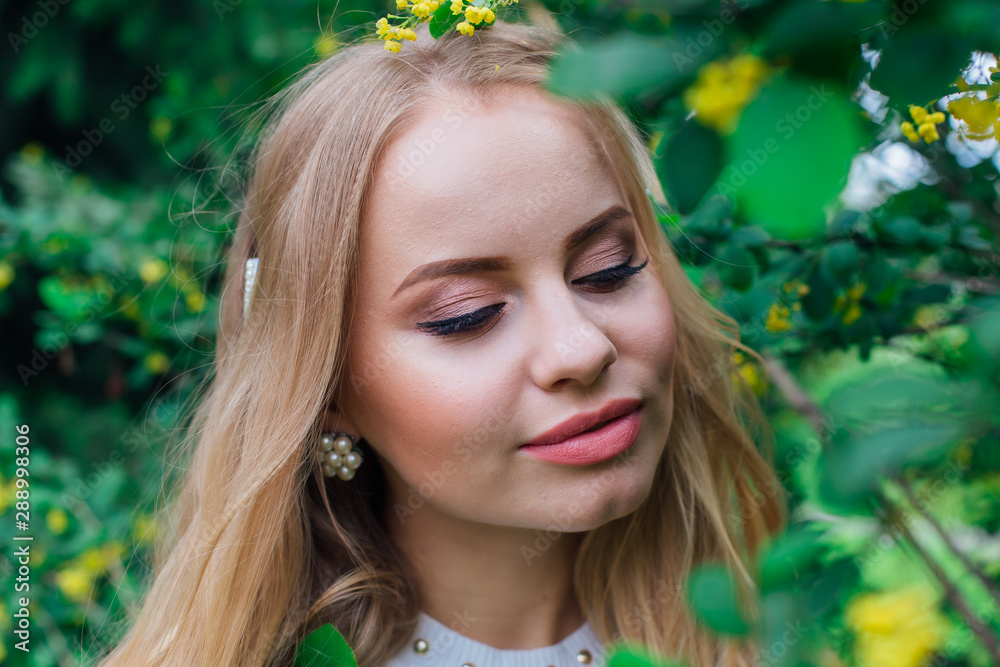 Close up portrait of a charming blond woman wearing beautiful white dress standing next to barberry bush. Close up portrait of a charming blond woman wearing beautiful white dress standing next to barberry bush.