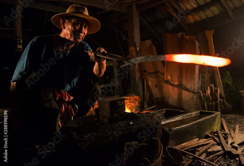 Professional Blacksmith at work is Hit the iron by a hot metal With fire