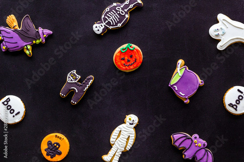 Halloween cookies in shape of spooky figures pattern on black background top view