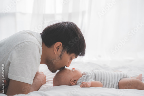 Tableau sur toile asian daddy kiss his baby boy on forehead while lying on the bed
