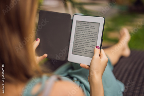 Woman reads e-book on deck chair in the garden photo