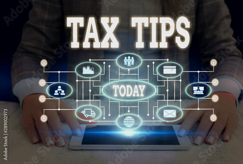 Writing note showing Tax Tips. Business concept for compulsory contribution to state revenue levied by government Woman wear formal work suit presenting presentation using smart device