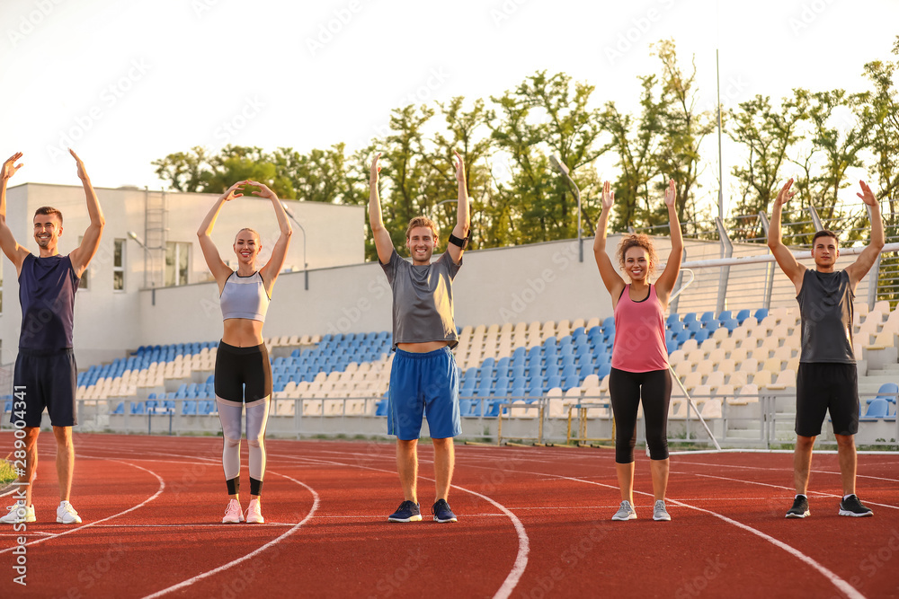 Group of sporty young people training at the stadium