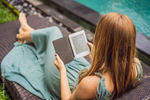 Woman reads e-book on deck chair in the garden photo